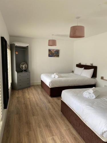 two beds in a room with wooden floors at Apt 4 - Silver Spruce in Killarney