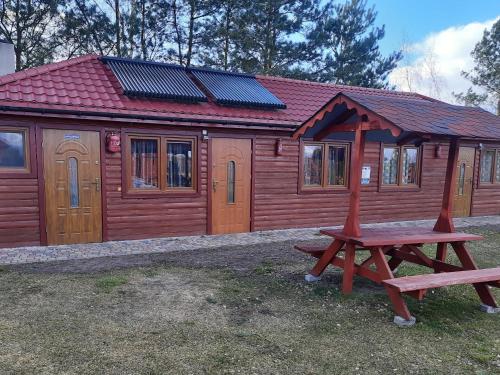 a wooden cabin with a picnic table in front of it at Agroturystyka nad Biebrza Sośniaki in Goniadz