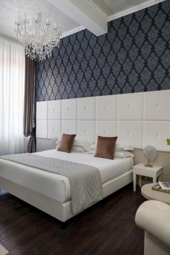 a bedroom with a large white bed and a chandelier at Albergo Rossini 1936 - Small & Charming in Bologna
