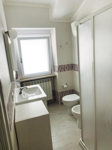 a bathroom with a toilet and a sink and a window at Suali Case nel Borgo in Civita Castellana