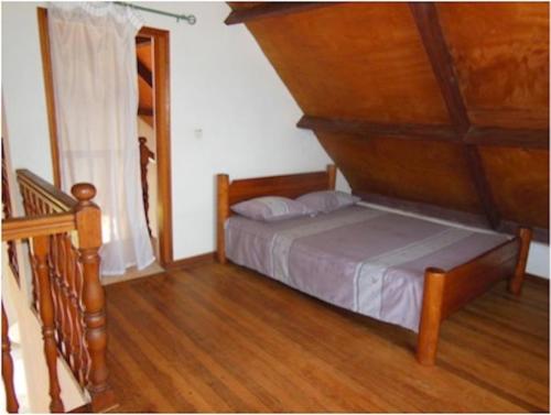 1 dormitorio con 1 cama y suelo de madera en SNI-Village Ambohidratrimo au bord du Lac Andranotapahana en Ambohidratrimo