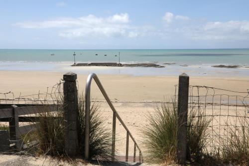 a sandy beach with a pier in the ocean at Les Maisons de Louise in Pirou