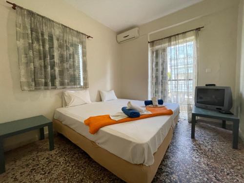 a bedroom with a bed with towels and a tv at Villa California in Paralia Dionysiou
