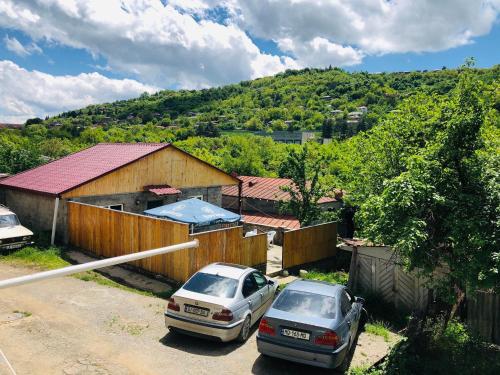 two cars parked next to a fence and a house at Guest house Babaka in Sighnaghi