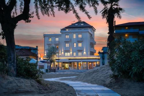 a large white building with a sunset in the background at Hotel Delfino in Caorle