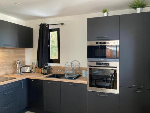 a kitchen with black cabinets and a stove top oven at Chez Marie-Pierre in Les Angles