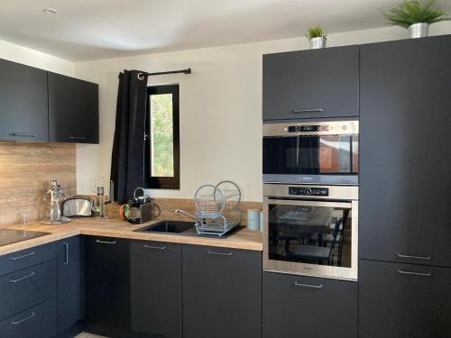 kuchnia z czarnymi szafkami i piekarnikiem w obiekcie Chez Marie-Pierre w mieście Les Angles