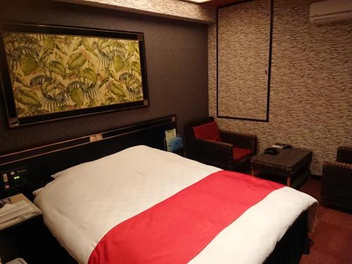 a hotel room with a bed and a painting on the wall at HOTEL Mythos (ホテル ミュートス) in Sakai