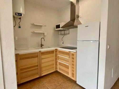 a kitchen with a white refrigerator and wooden cabinets at Apartamento para 4-5 personas en es Pujols, Formentera in Es Pujols