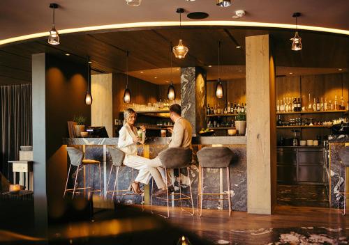 two people sitting at a bar in a restaurant at Hotel Bad Fallenbach in San Leonardo in Passiria