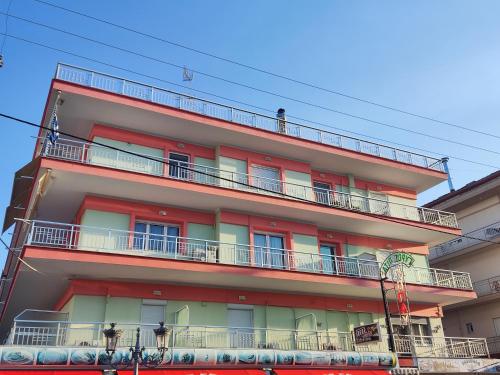 a red building with balconies on the side of it at Studios Dafni in Paralia Katerinis