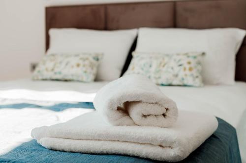 a pile of towels sitting on a bed at Natura Luxury Suites Parga in Parga