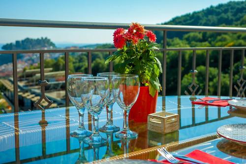 a table with wine glasses and a vase with a flower at Natura Luxury Suites Parga in Parga