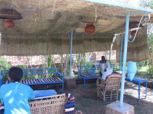 a man sitting on a chair under a tent at Bet El Kerem Guesthouse in Aswan