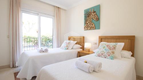 1 dormitorio con 2 camas con sábanas blancas y ventana en Spacious perfectly maintained house with private garden and communal pool in Riviera del Sol, en Málaga
