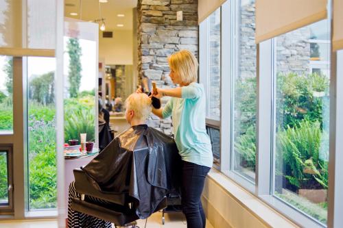 a woman cutting a mans hair in a salon at The Sidney Pier Hotel & Spa in Sidney