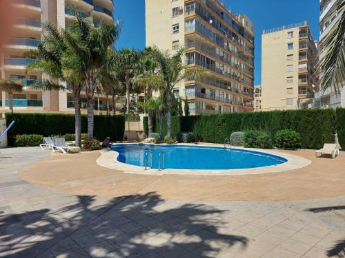 una piscina en un patio con palmeras y edificios en Rocasol - Suites, en Calpe