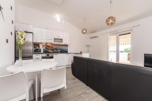 a kitchen with white cabinets and a white table and chairs at Apartments Maza in Zadar