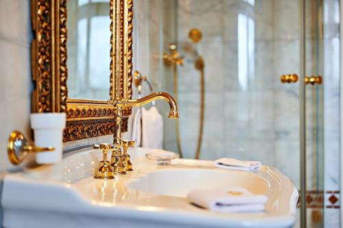 a bathroom sink with a gold faucet and a mirror at Bernsteinschloss in Wendorf