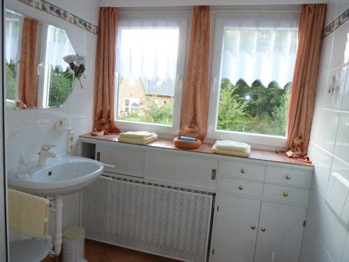 ein Badezimmer mit einem Waschbecken und zwei Fenstern in der Unterkunft Gästehaus Villa Kreativ Susanne Lay in Bad Münder am Deister