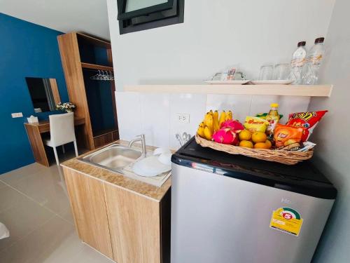 a kitchen with a basket of fruit on top of a refrigerator at OYO 75403 Dinosaur Apartment in Hua Hin