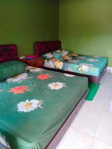 two twin beds in a room with green walls at penginapan Samara Homestay Tawangmangu in Tawangmangu