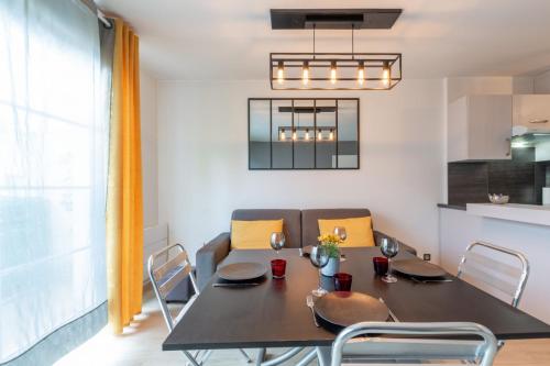 a dining room with a black table and chairs at Sunshine by Plaza - Proche Disneyland Paris in Montévrain