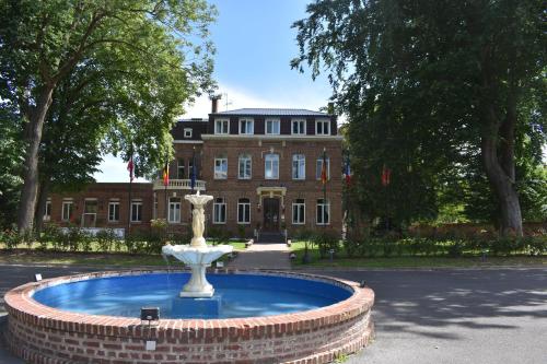 a fountain in front of a building with a building at Logis Manoir de Fourcy in Corbehem