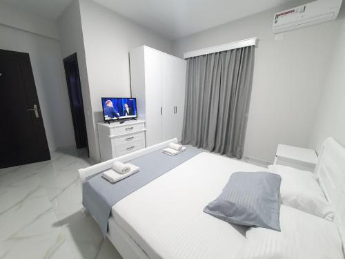 una camera da letto bianca con un letto grande e una televisione di IL MIO a Ksamil