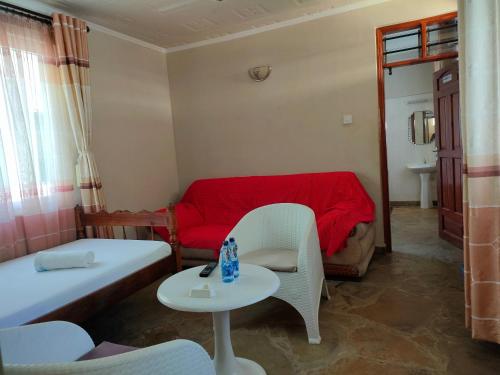 a room with a bed and a table and a couch at Prime Comfort HOTELS & Apartments Mtwapa in Mtwapa