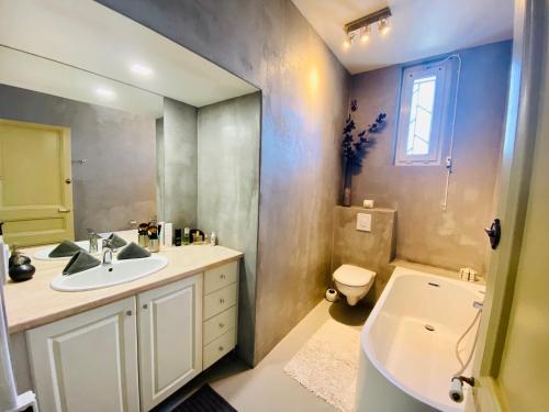 une salle de bain avec un lavabo, une baignoire et des toilettes dans l'établissement ''Les Halles'' Maison de ville avec piscine et garage aux Halles, à Sète