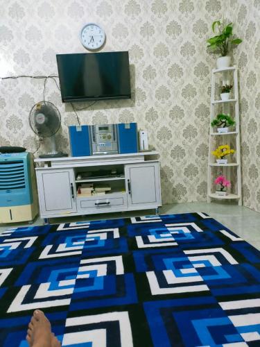 a living room with a tv and a blue and white rug at Shifana homestay syariah in Yogyakarta