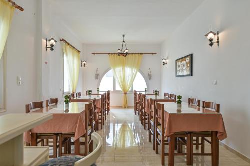una sala da pranzo con tavoli, sedie e una finestra di Hotel Zeus a Naxos Chora