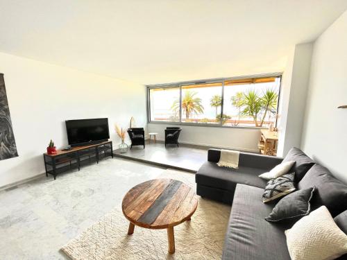 uma sala de estar com um sofá e uma mesa em Plage Landsberg Appartement 2 pièces en bord de mer em Saint-Laurent-du-Var