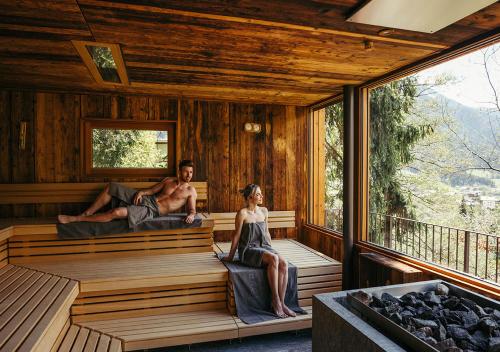 a man and a woman sitting in a sauna at Hotel Bad Fallenbach in San Leonardo in Passiria