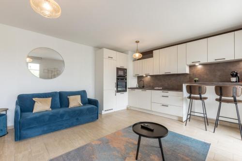 un salon avec un canapé bleu et une cuisine dans l'établissement Family Garden by Plaza - Proche Disneyland Paris, à Chessy