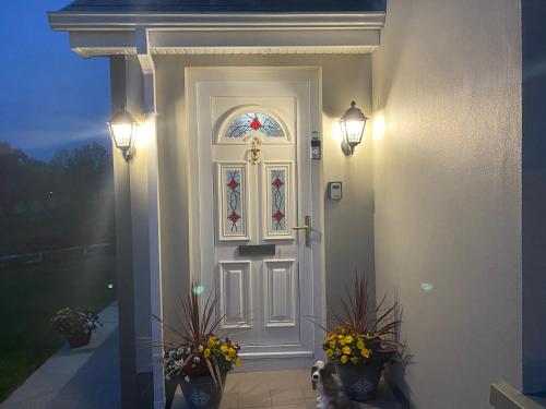 een witte deur met een glas-in-loodraam en bloemen bij Corraglass House - close proximity to Cuilcagh in Letterbreen