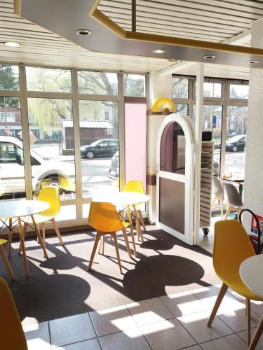 a cafeteria with tables and chairs and a window at EGG HOTEL - HOTEL LES GENS DE MER Dieppe in Dieppe
