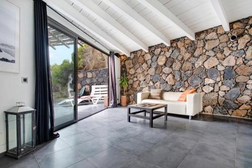 a living room with a couch and a stone wall at La Bodeguita House in Haría