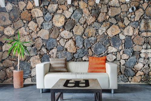 a living room with a white couch and a stone wall at La Bodeguita House in Haría