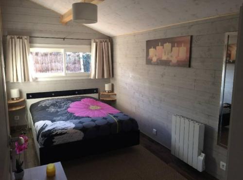 a bedroom with a bed with a pink flower on it at Adorable chalet des Huttiers - Bassin d'Arcachon in Audenge