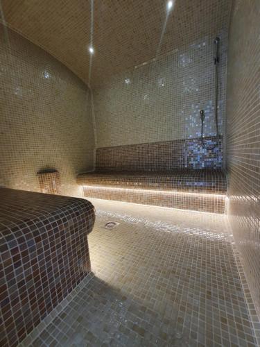 a tiled bathroom with a tub with a shower at Panoráma Lux Wellness apartman in Hajdúszoboszló