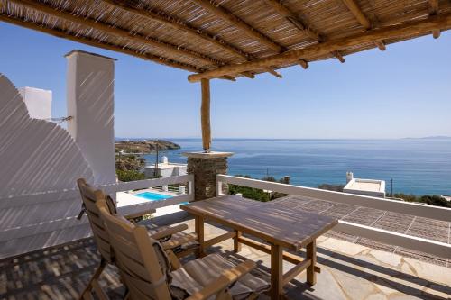 un patio con mesa, sillas y el océano en Big Blue Suites & Apartments en Kionia