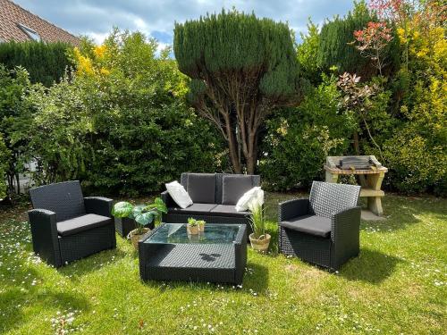 a yard with three chairs and a table and a tree at Les Mouettes in Escalles