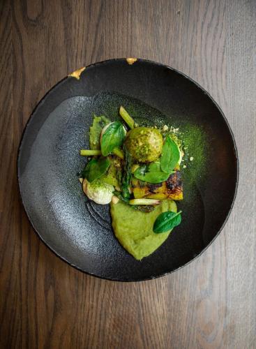 a black plate of food with vegetables on a table at CRU Hotel in Tallinn