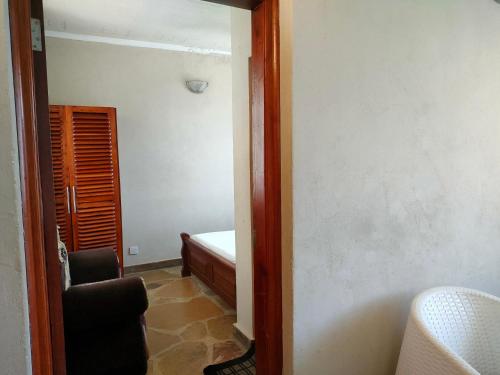 a room with a bedroom with a bed and a mirror at Prime Comfort HOTELS & Apartments Mtwapa in Mtwapa