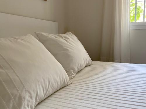 a bed with two white pillows on top of it at APARTAMENTO PLAZA ESPAÑA in Écija