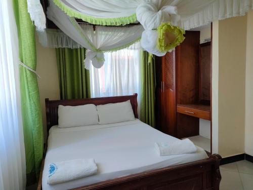 a bedroom with a bed with a canopy and curtains at Prime Comfort HOTELS & Apartments Mtwapa in Mtwapa