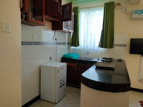 a small kitchen with a counter and a refrigerator at Prime Comfort HOTELS & Apartments Mtwapa in Mtwapa