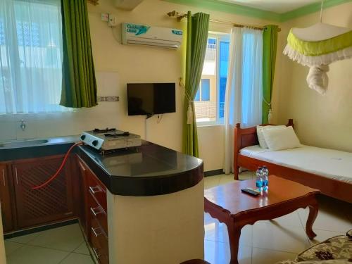 a small room with a bedroom with a bed and a table at Prime Comfort HOTELS & Apartments Mtwapa in Mtwapa